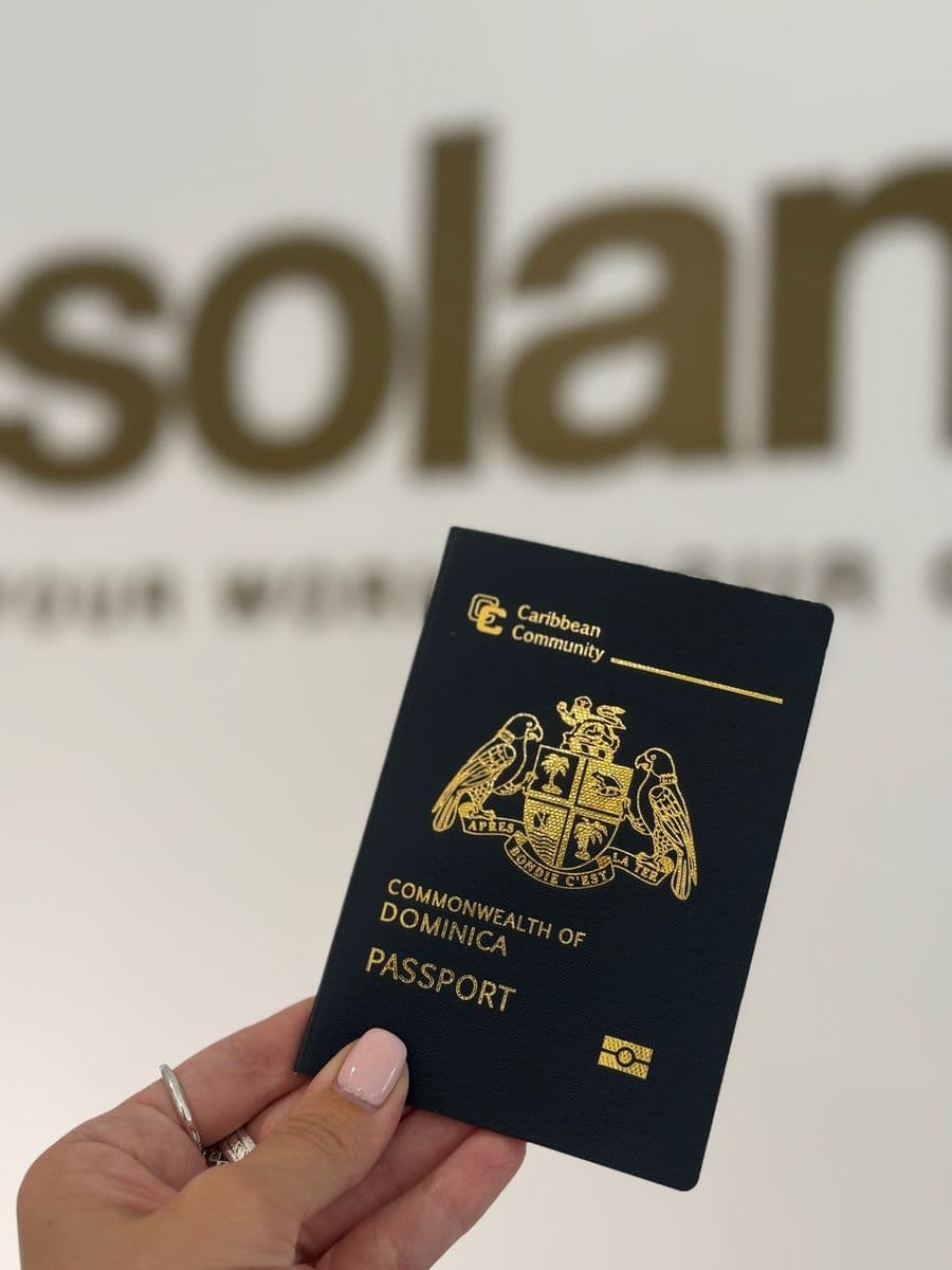 A Dominica passport held up in front of the Soland sign