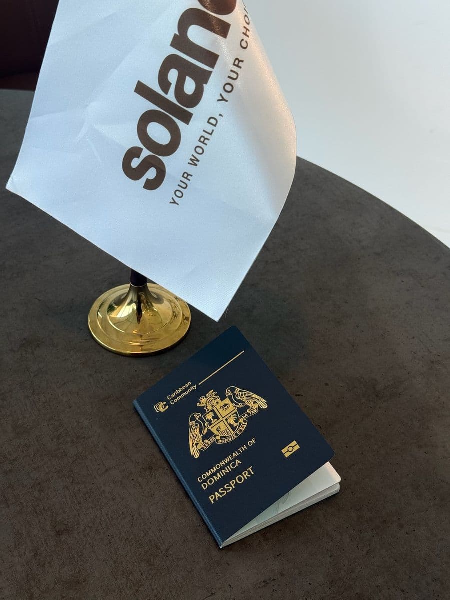 A Dominica passport on a table beside the Soland desk flag
