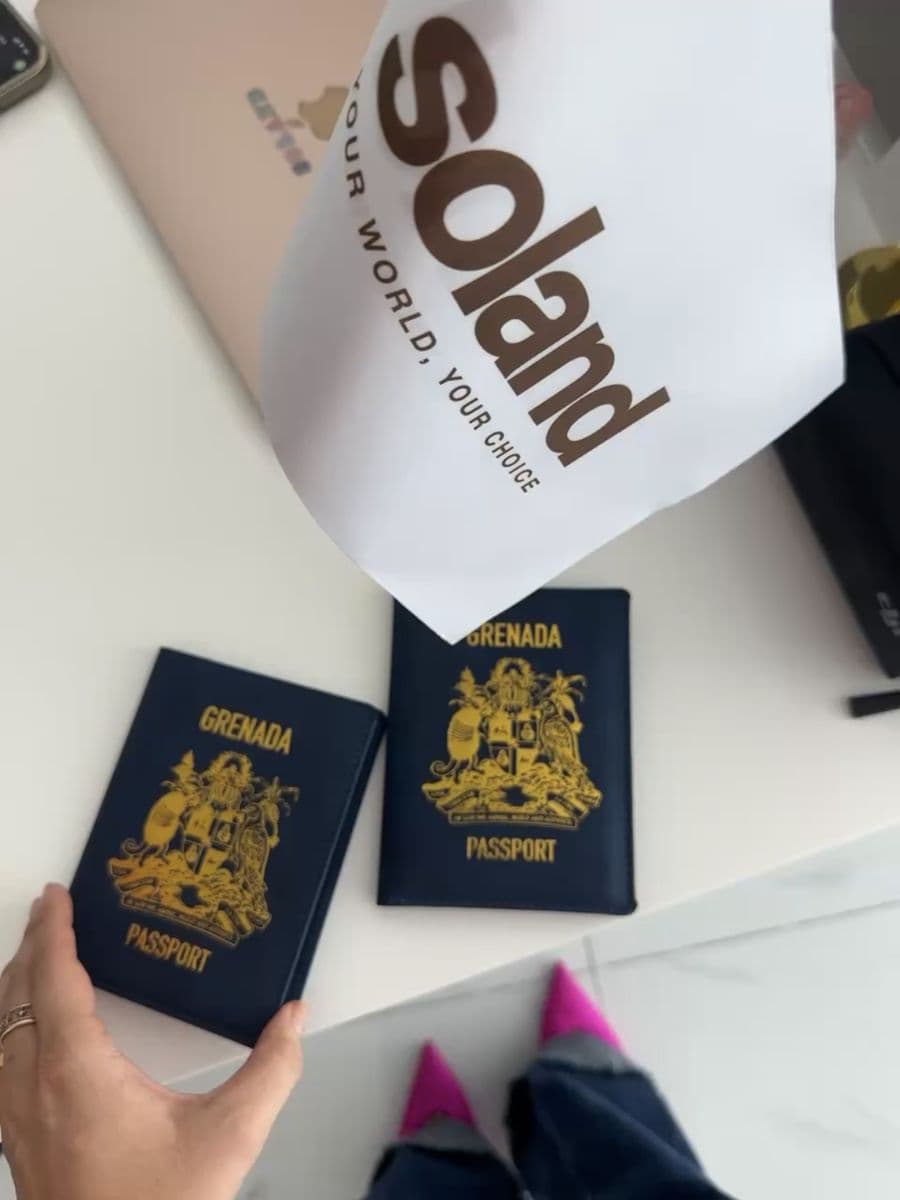 Two Grenada passports on a desk under the Soland flag